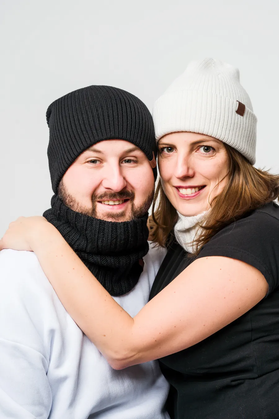 Couple in black and cream beanies and neck warmers from the private label collection