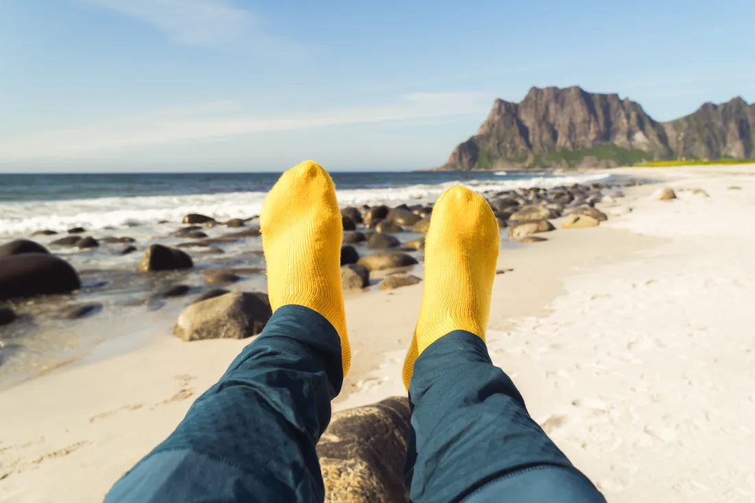 Yellow knitted socks on a beach — knitwear for all seasons
